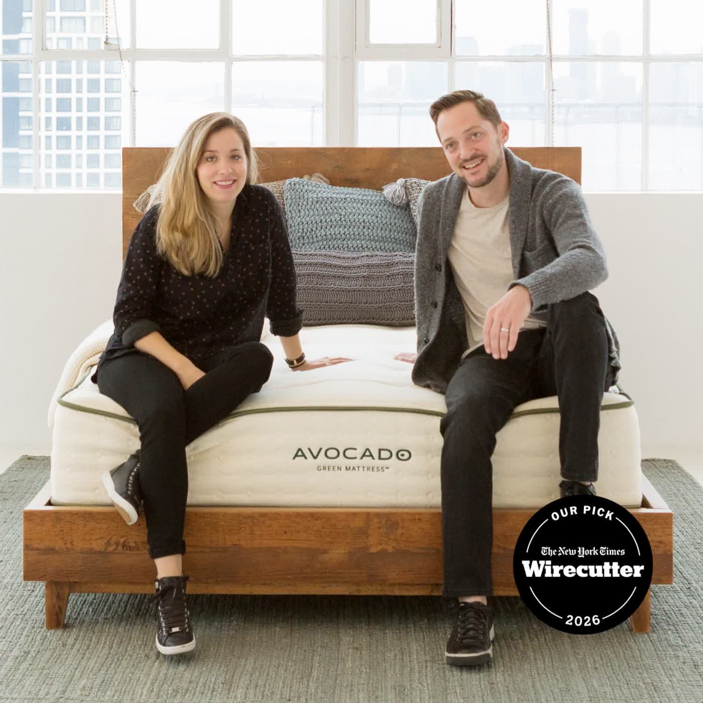 Avocado Green mattress on a wooden bed frame in a plant-filled bedroom
