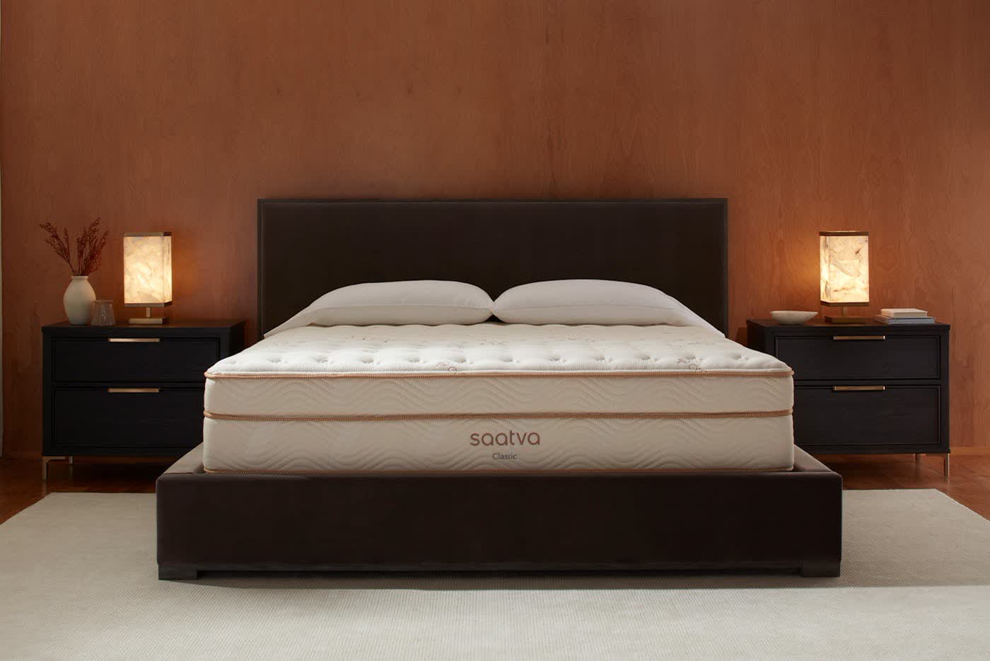 Saatva Classic mattress styled on a dark upholstered bed frame